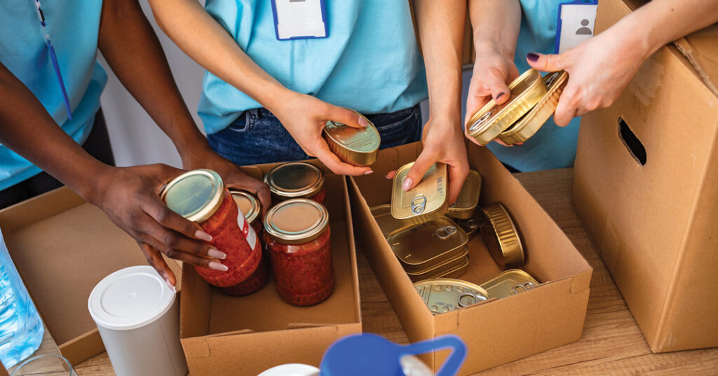 Volunteers sorting canned food and homemade preserves into donation boxes to support a community food program.